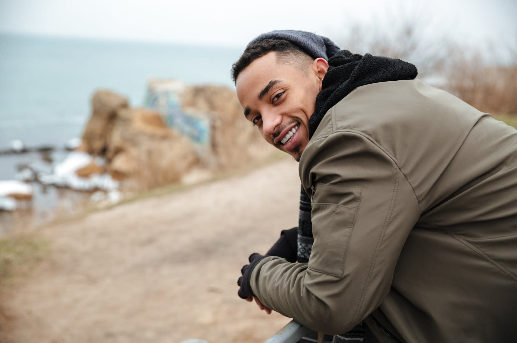 A young man smiling outdoors near the coast