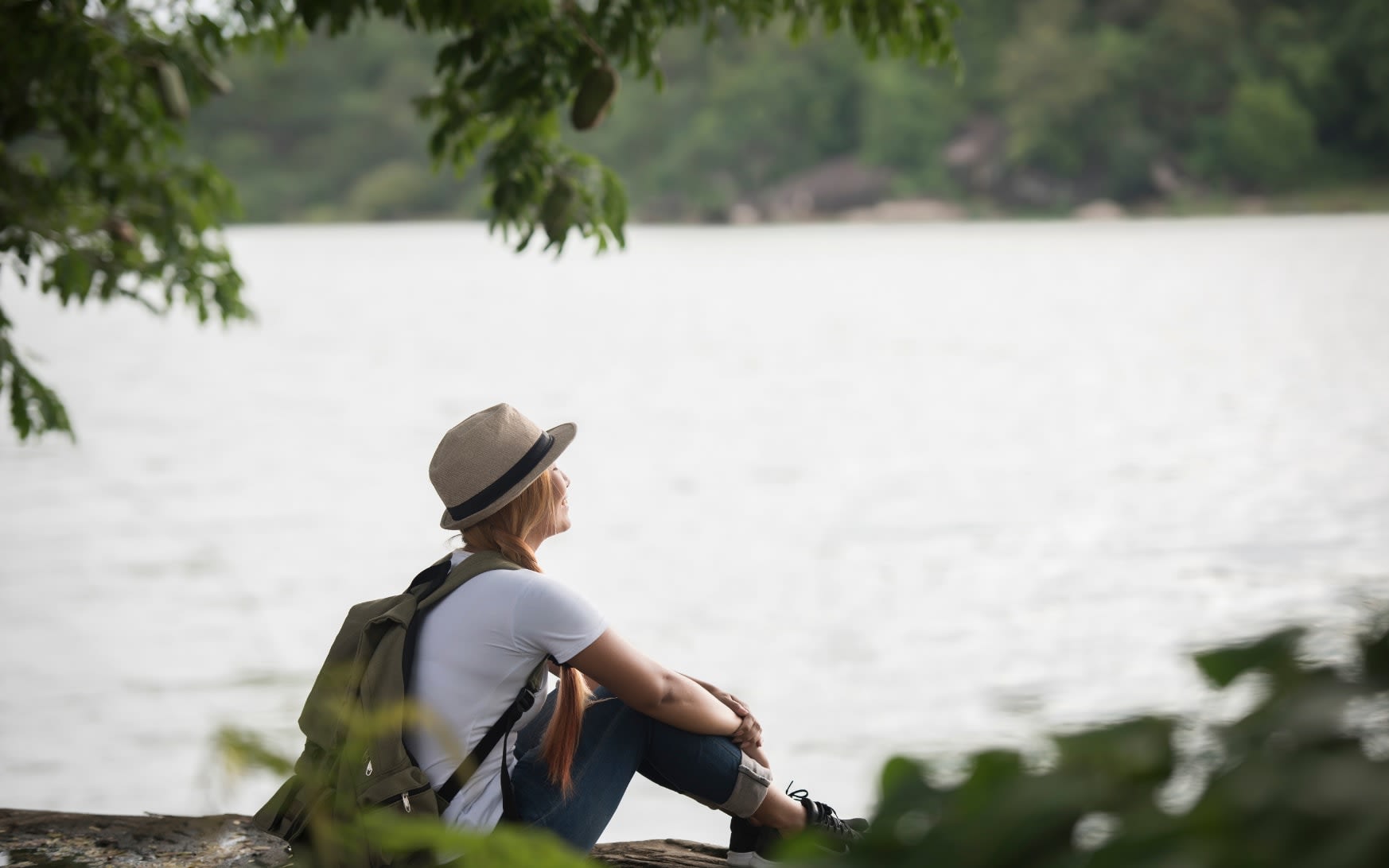 A person sitting quietly by the water, reflecting